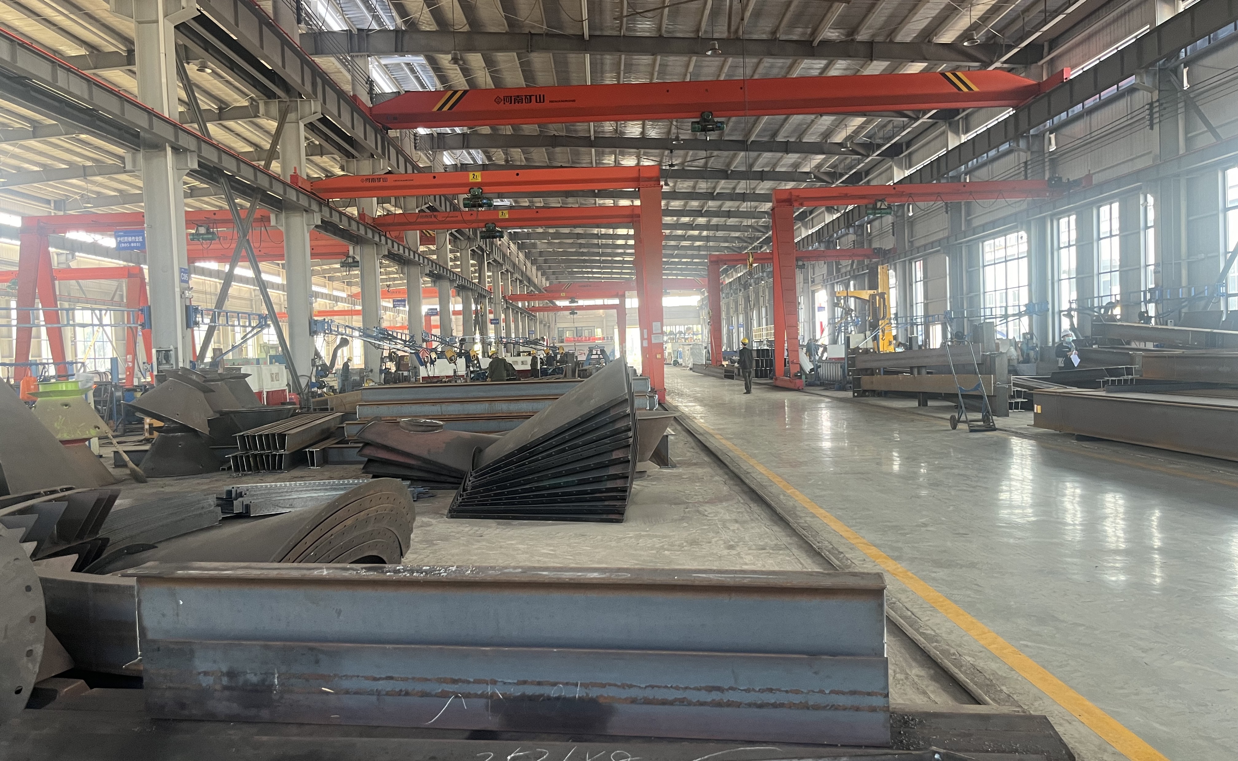 Steel fabrication workshop with overhead cranes, production lines and steel inventory