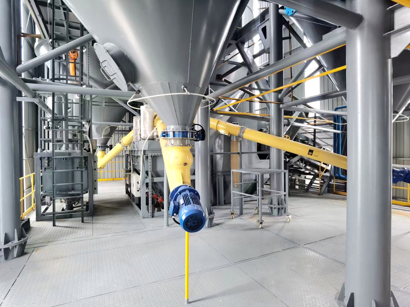 Yellow screw conveyors installed below dry bulk material hoppers